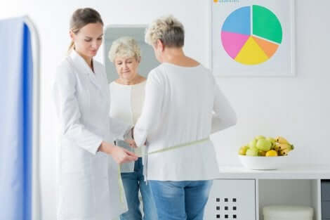 A woman at the doctor's office getting her waist measured.