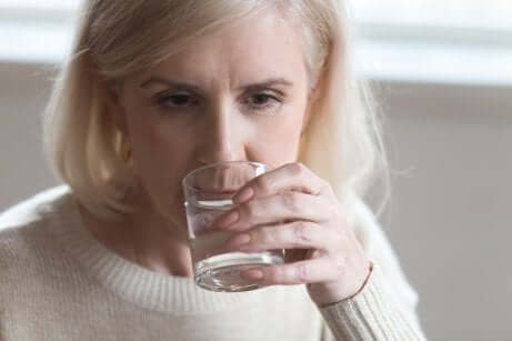 An older woman drinking water.
