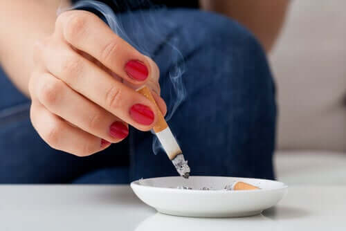 A woman putting out a cigarette in an ash tray.