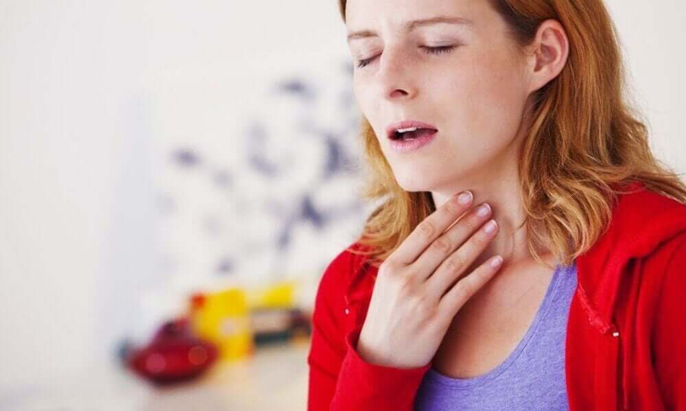A woman toughing her neck with a painful look on her face.