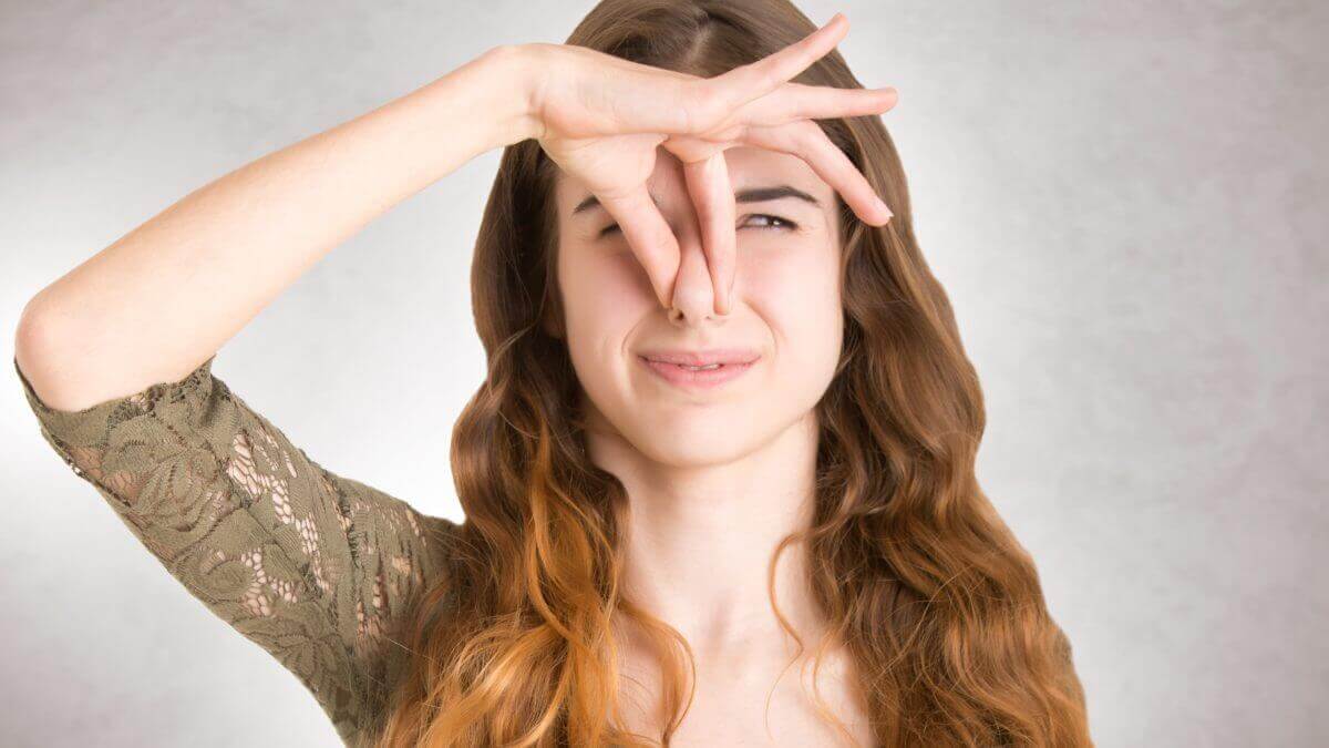 A woman unplugging her nose because of an unpleasant smell.