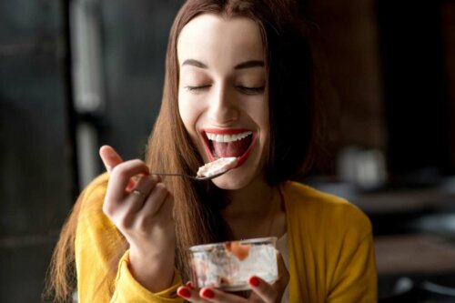 A smiley woman eating yogurt.