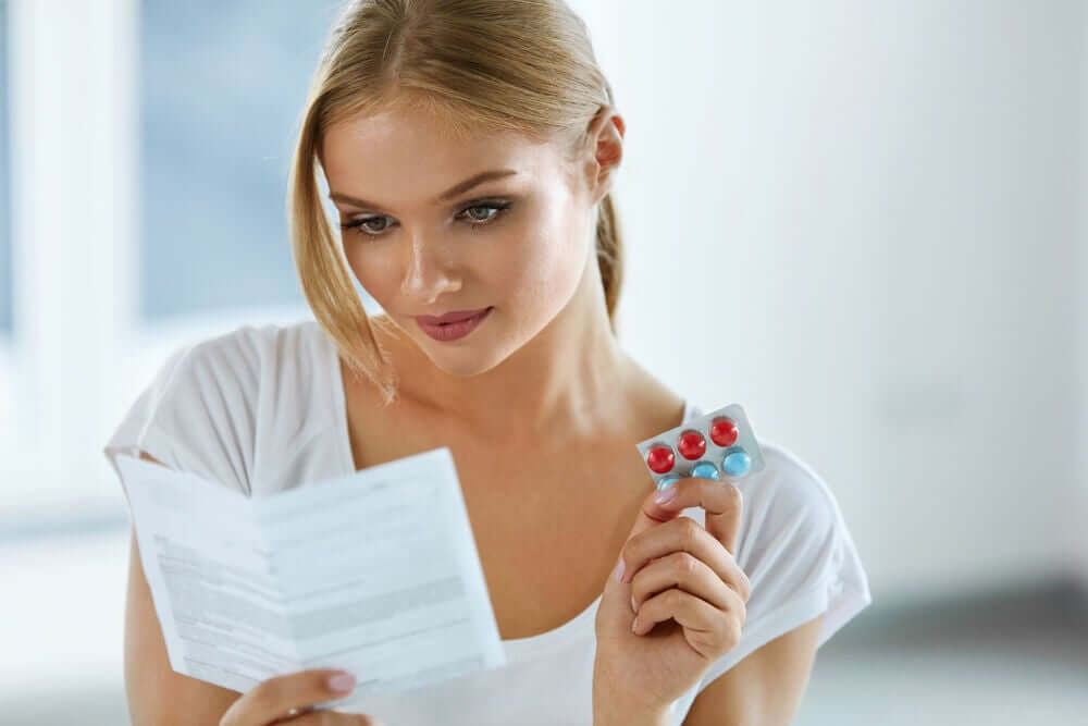 A woman reading information about the medication she's holding in her hand.