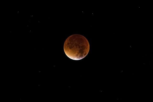 A picture of the moon with a reddish hue.