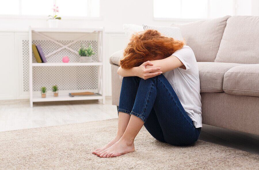 A woman sitting on the floor crying.
