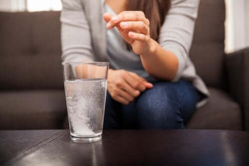 Kvinde kommer syreneutraliserende midler i et glas vand