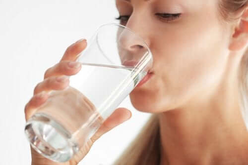 Μια γυναίκα πίνει ένα ποτήρι νερό.