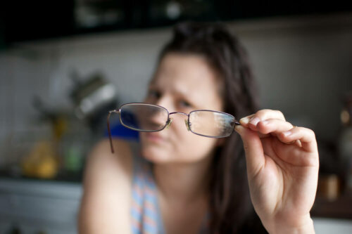A woman looking at her glasses.