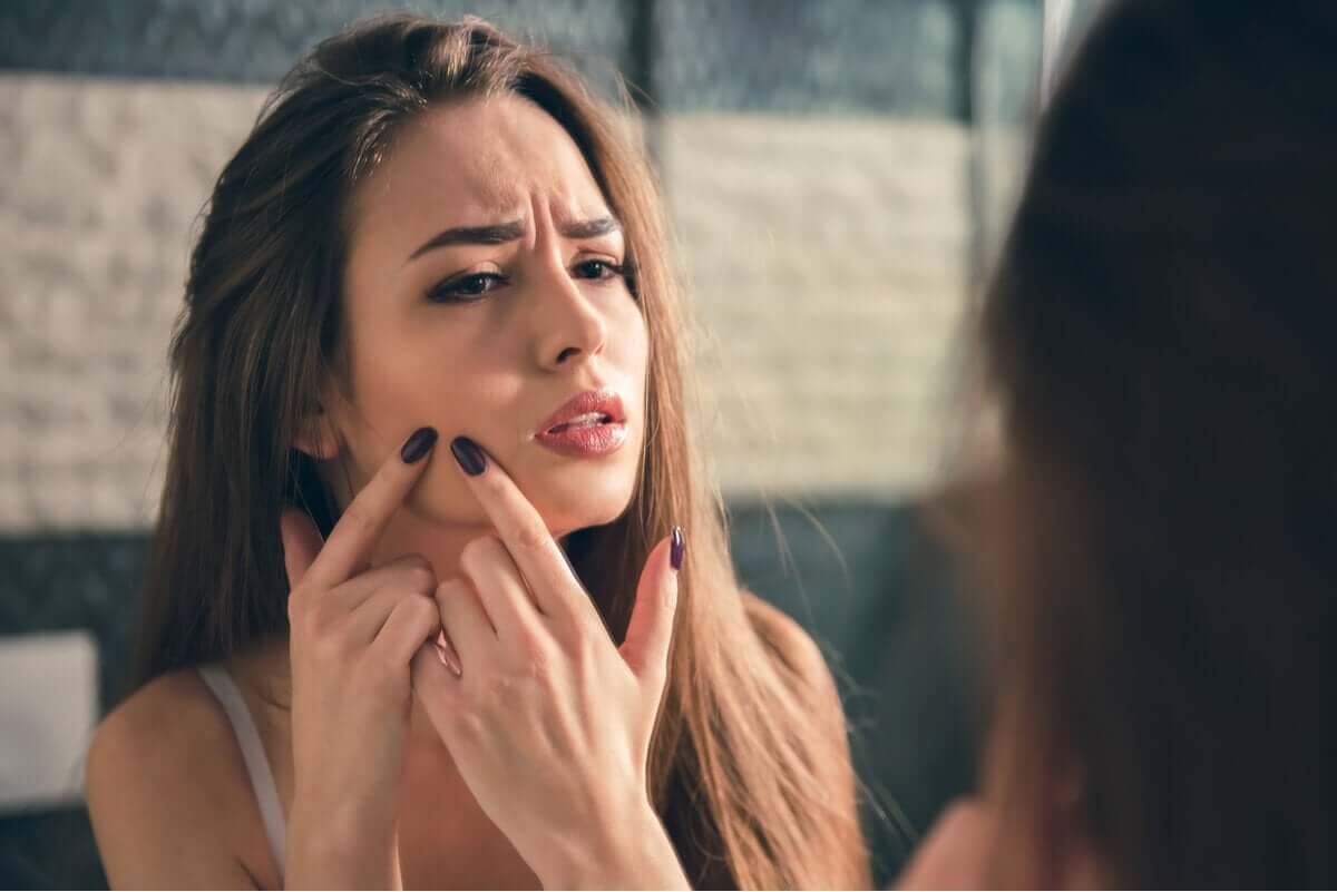 A woman popping a pimple on her cheek.