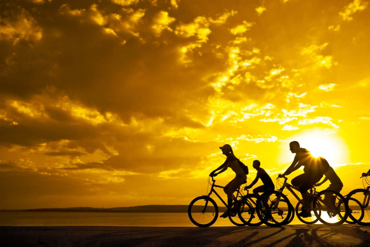 Rodzina jeżdżąca na rowerach o zachodzie słońca.