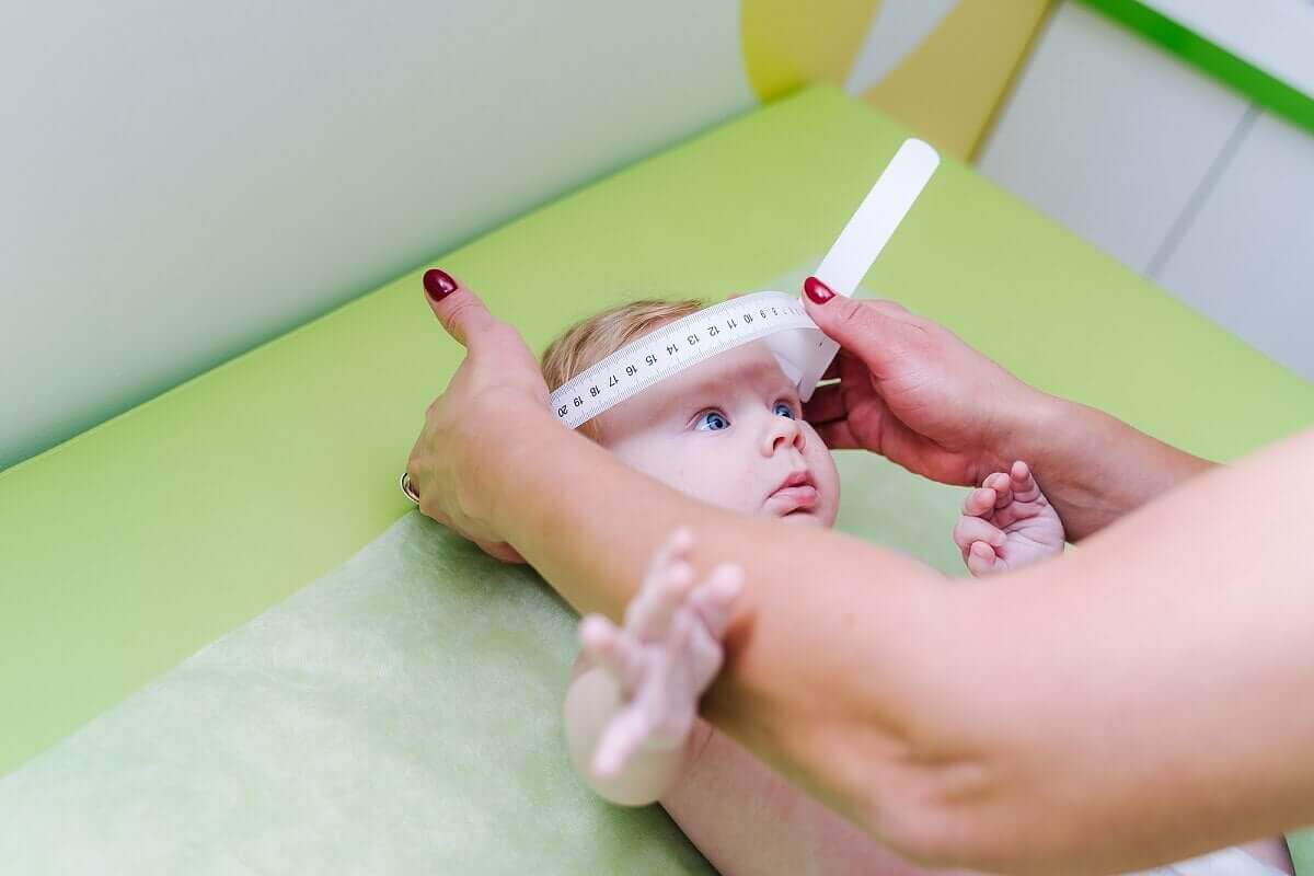 A pediatrician measuring a baby's cranium.