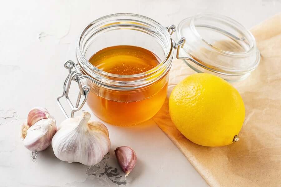 A head of garlic, a jar of honey, and a lemon.