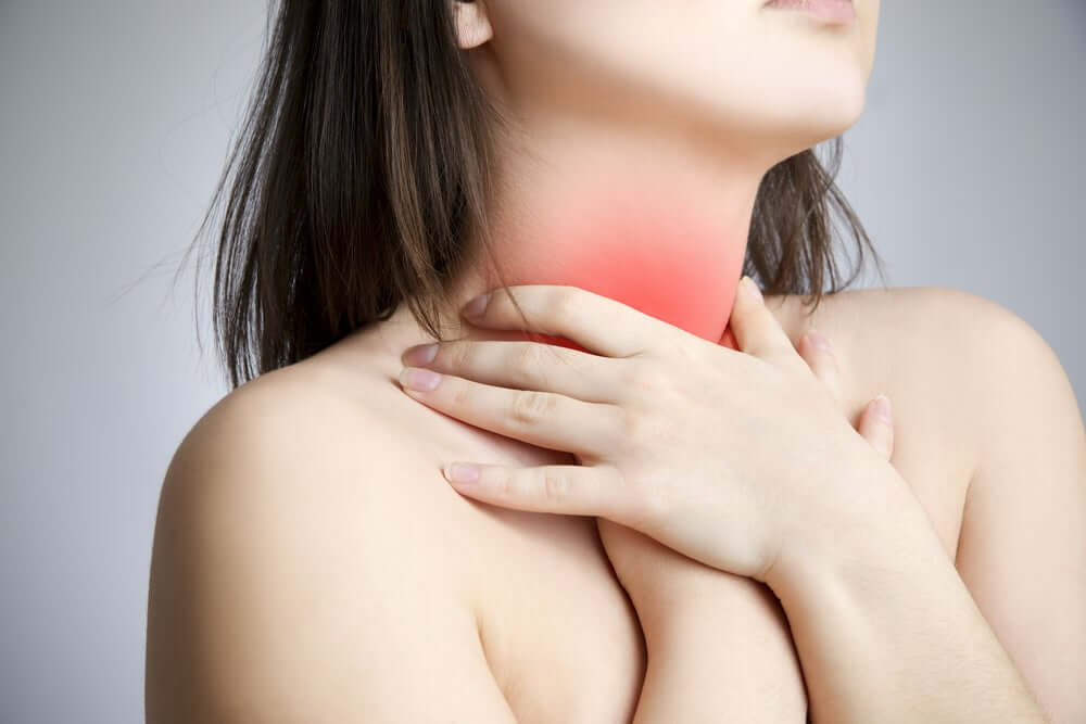 A woman holding onto her sore throat.