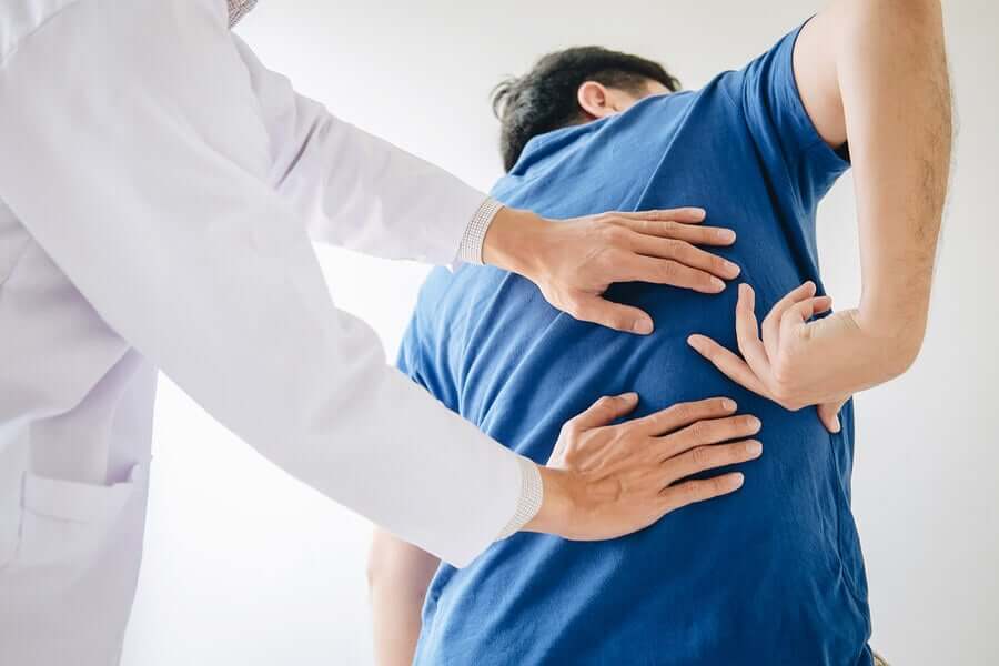 En mann viser legen en flekk på ryggen.