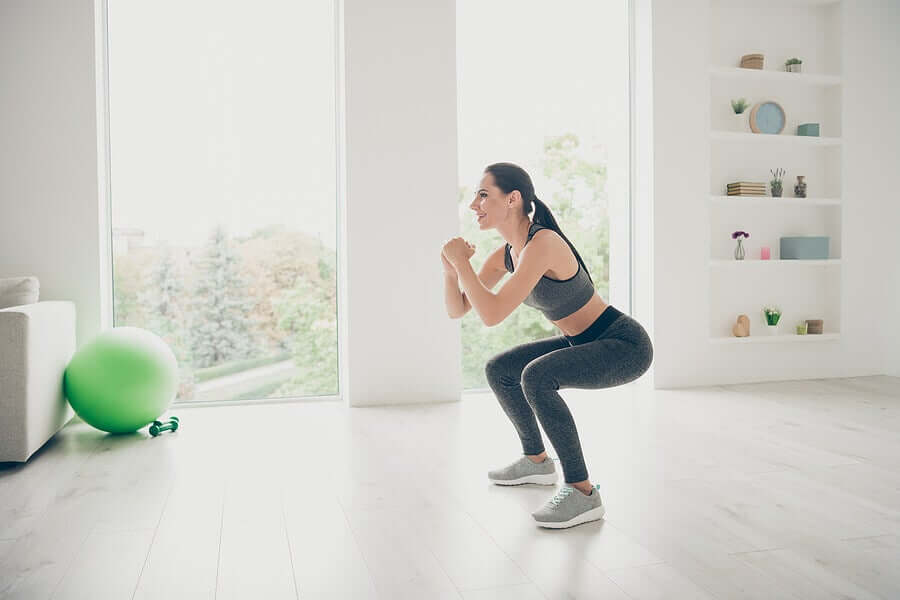 A woman performing squats as knee-strengthening exercises.