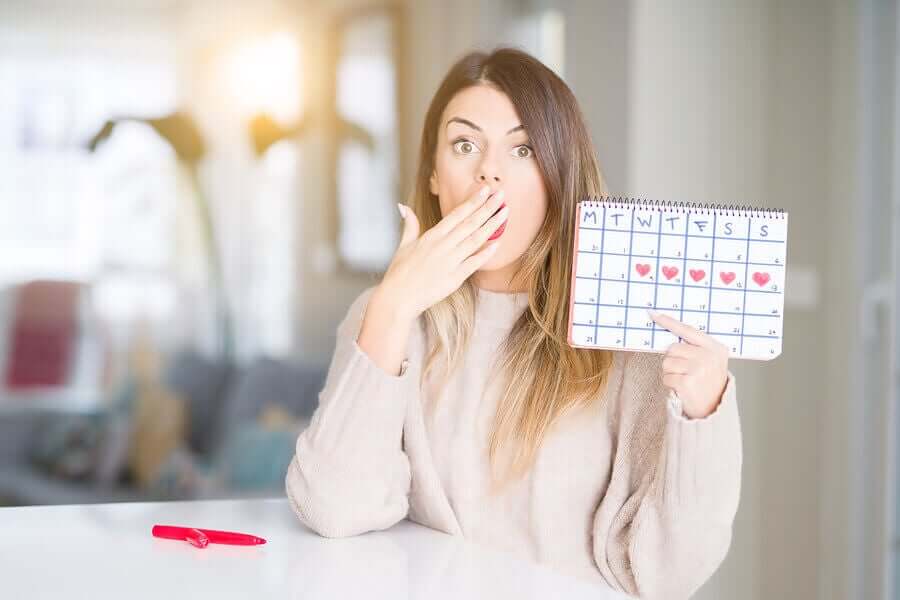 A woman holding up a calendar of her menstrual cycle.