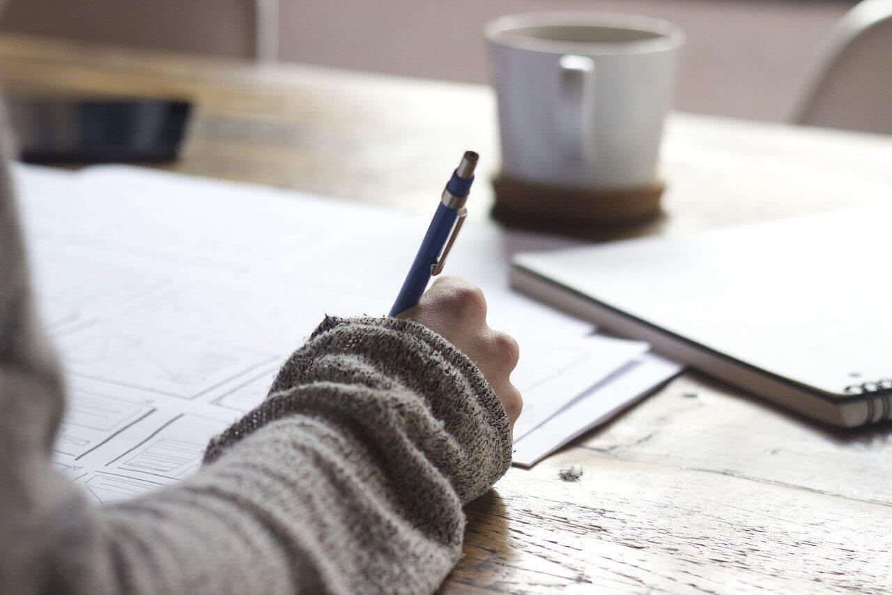 A woman writing with a pen and paper.