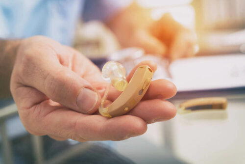 Doctor holding hearing aid out to patient.