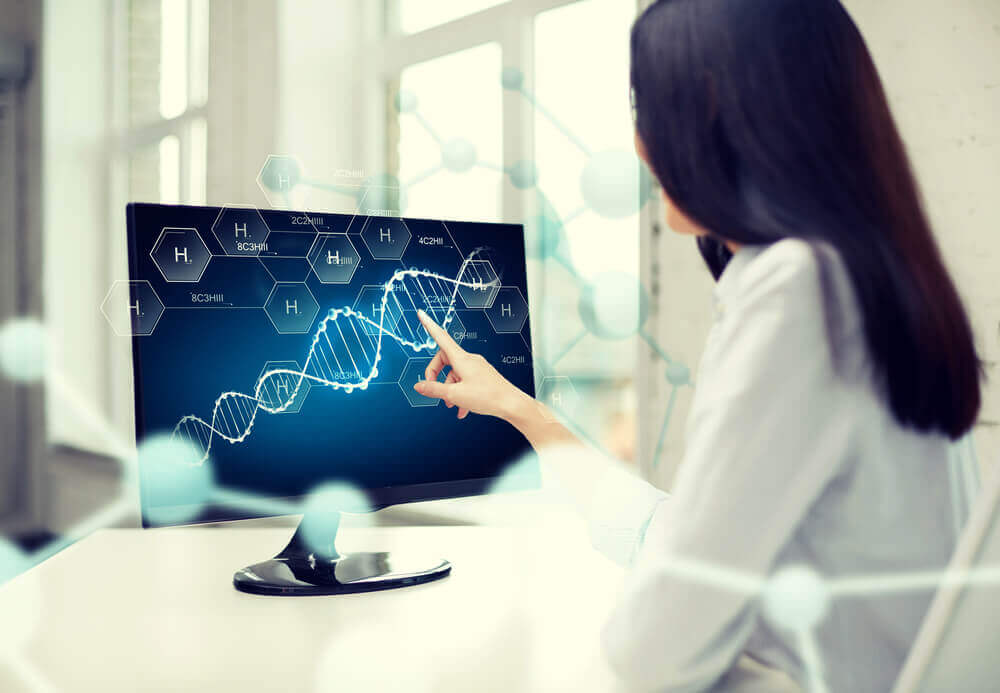 A doctor looking at a strand og DNA on a computer screen.