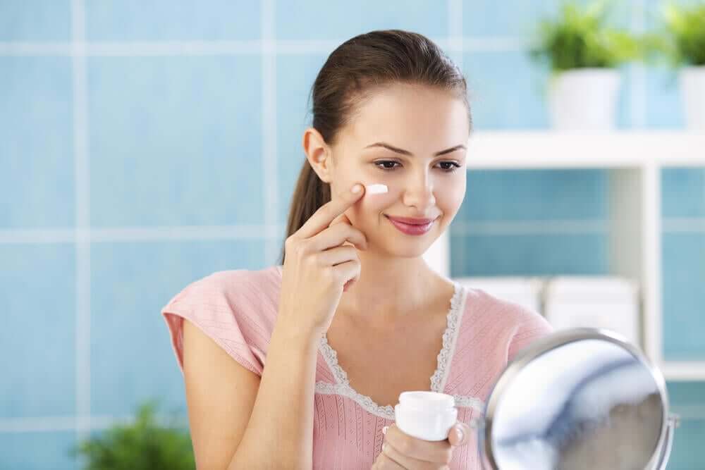 Kvinde påfører creme i ansigtet for at behandle atopisk hud