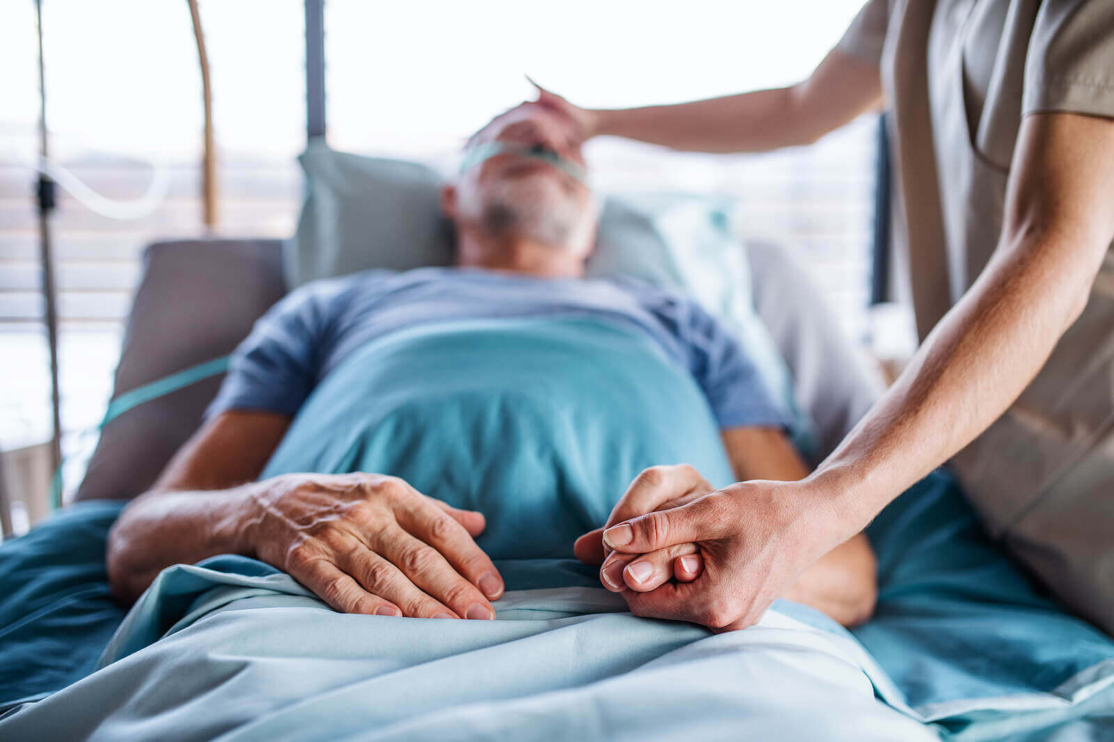 A nurse caring for a bedridden male patient.
