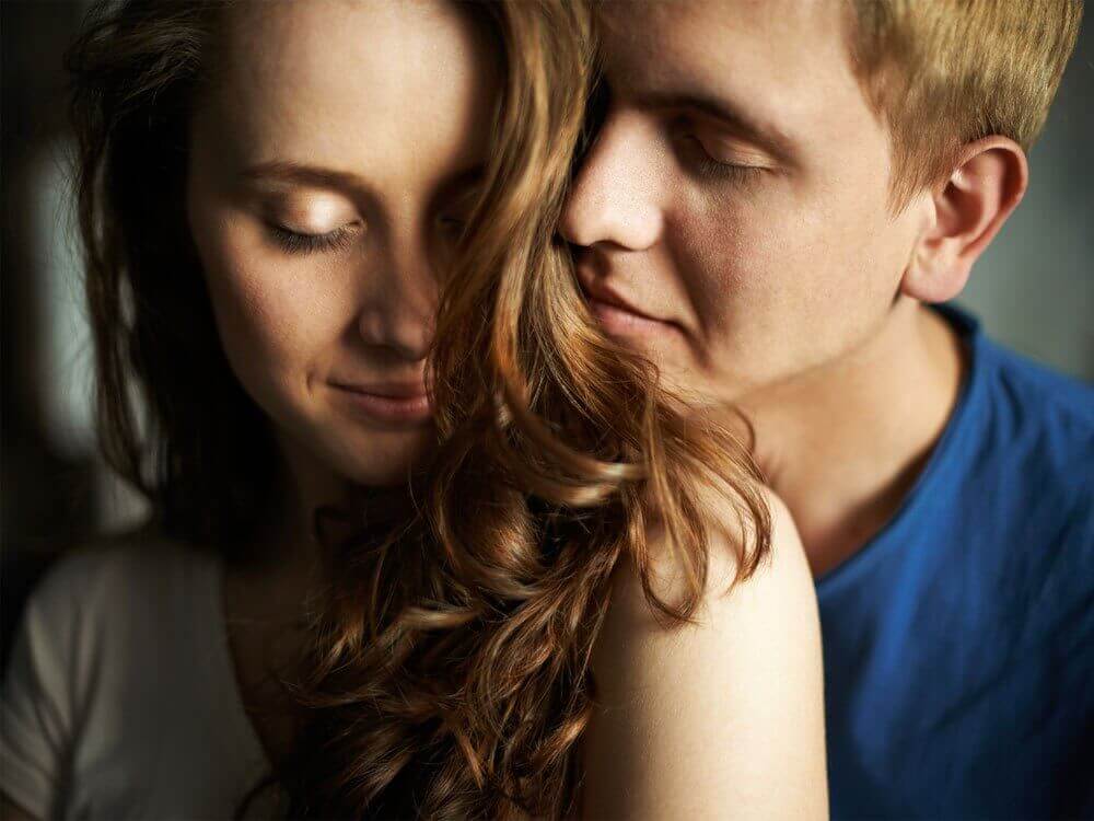 A man resting his head on his love's shoulder, looking at her lovingly.