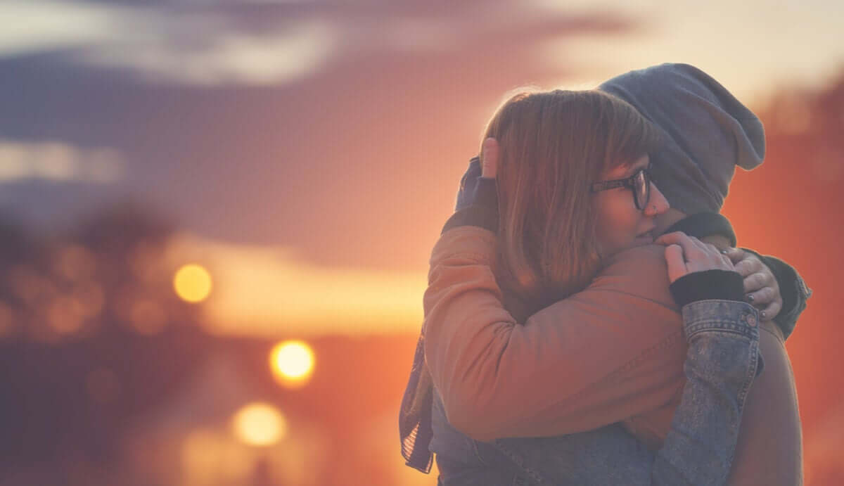 A couple embracing with a sunset in the background.
