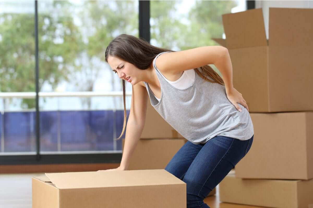 A woman with lower back pain from lifting a heavy box.
