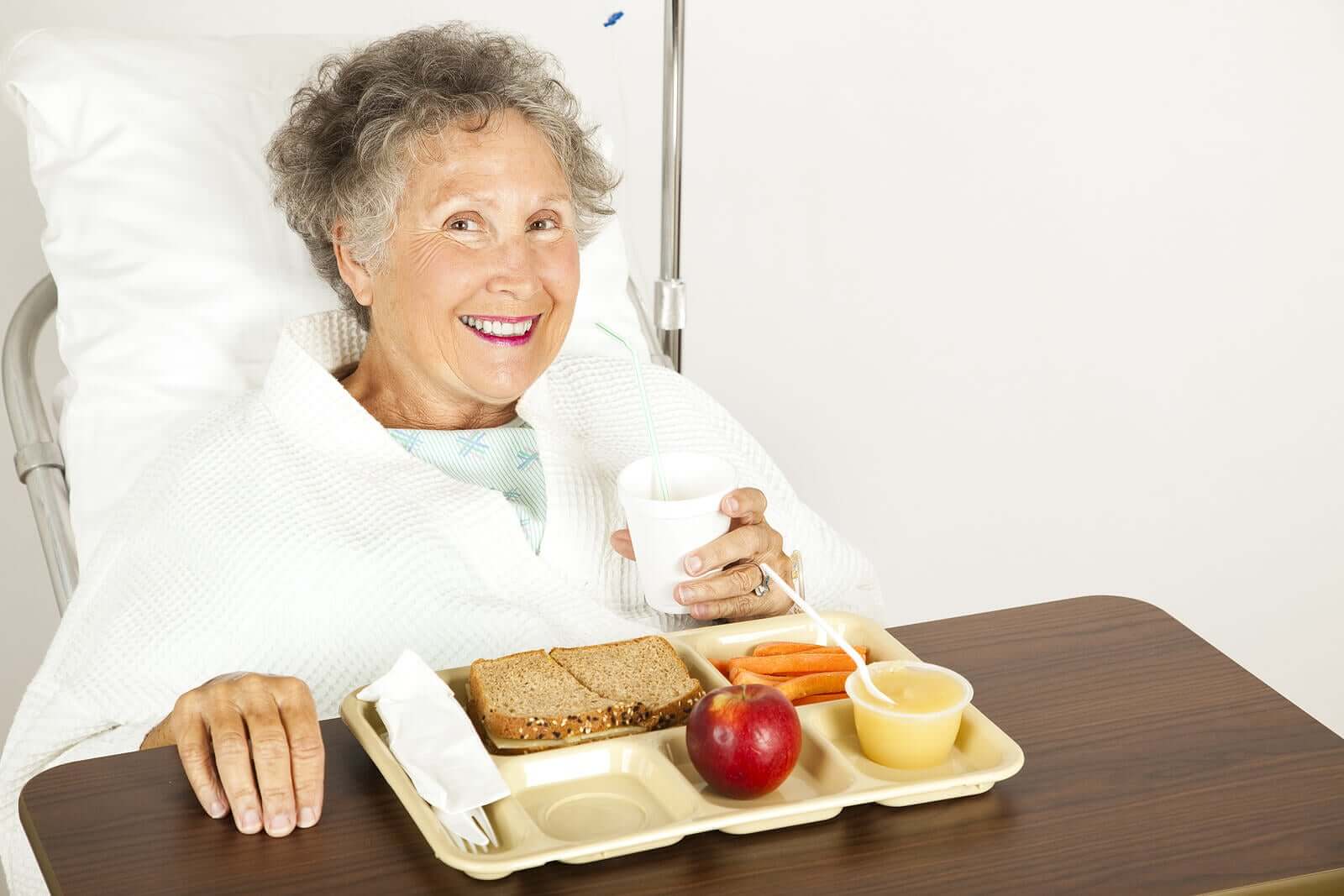 A bedridden woman eating off a hospital tray.