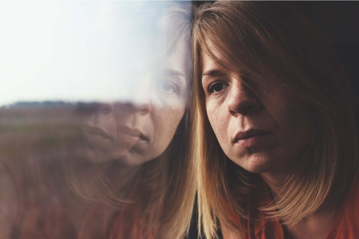 A woman leaning up against a window feeling discouraged.