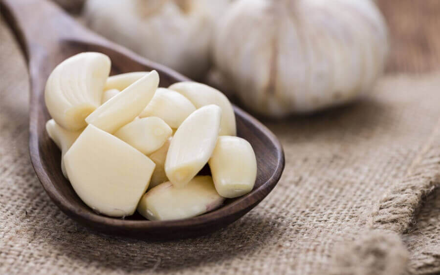 Peeled garlic cloves in a wooden spoon.