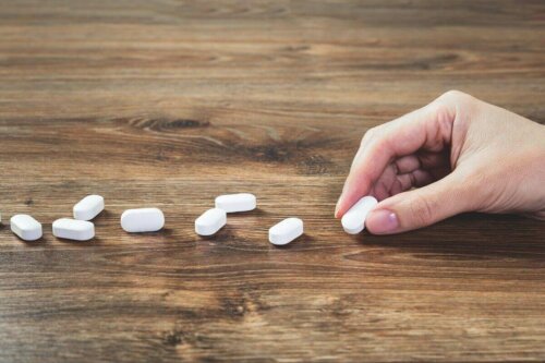 hand laying out pills on a wooden table