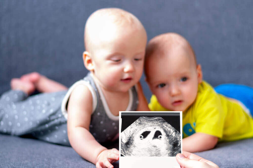 Twin baby boys holding a picture of their ultrasound.