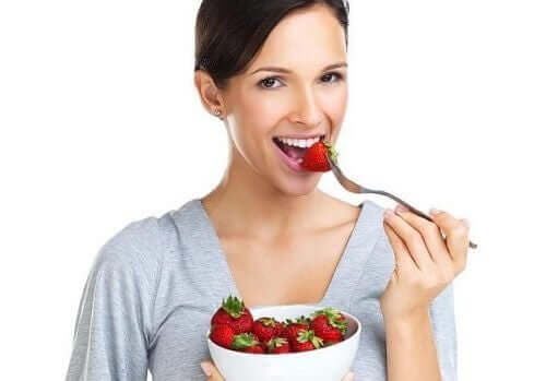 En kvinne som spiser en jordbær