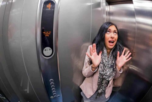 A woman panicking inside an elevator.