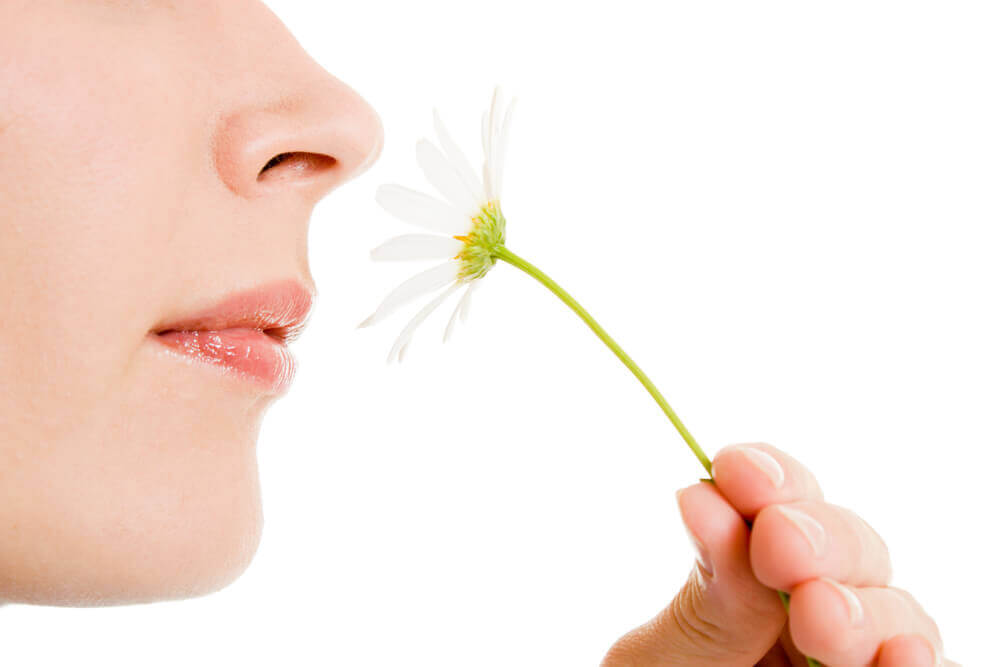 En kvinne som lukter på en blomst