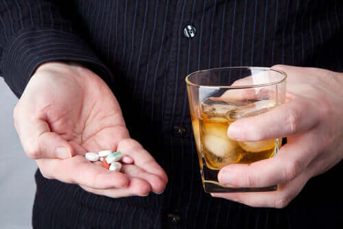 A person mixing pills with alcohol.