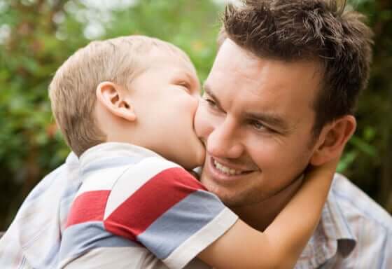 A small boy kissing his dad on the cheek.