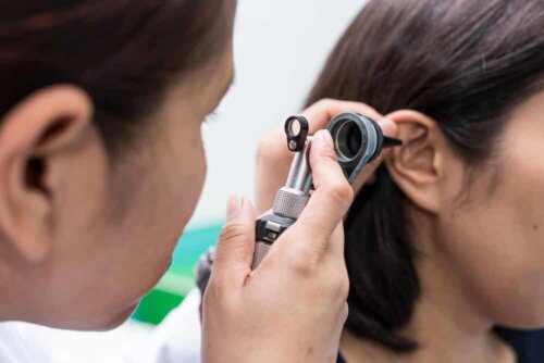 Læge tjekker kvindes øre for cerumen impactum