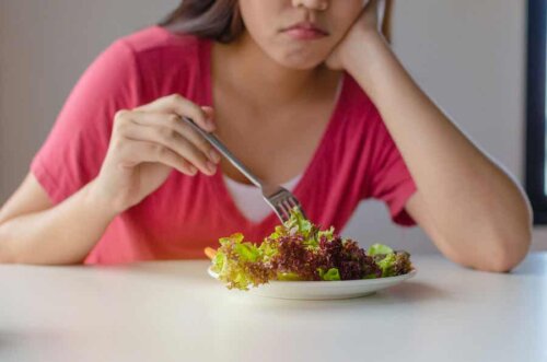 A woman trying to eat a salad.