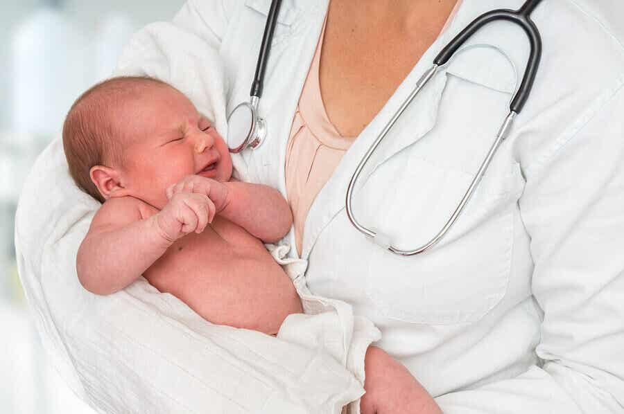 En lege som holder en nyfødt baby.