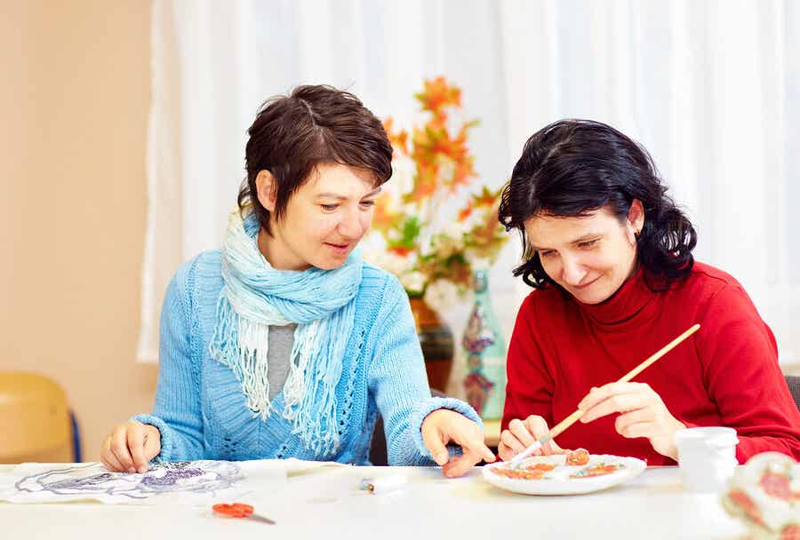 To kvinner gjør håndverk ved et bord.