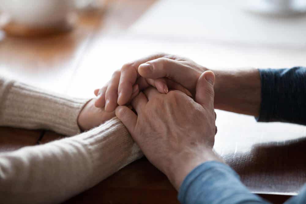 Abulia: two people holding each others' hands supportively.