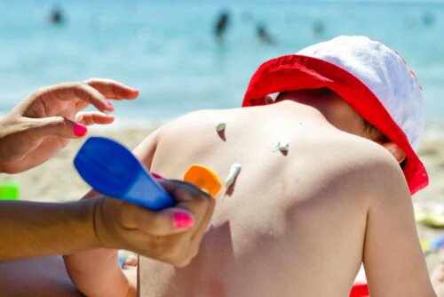 Fotoochrona dla dzieci: matka nakłada krem przeciwsłoneczny na skórę dziecka