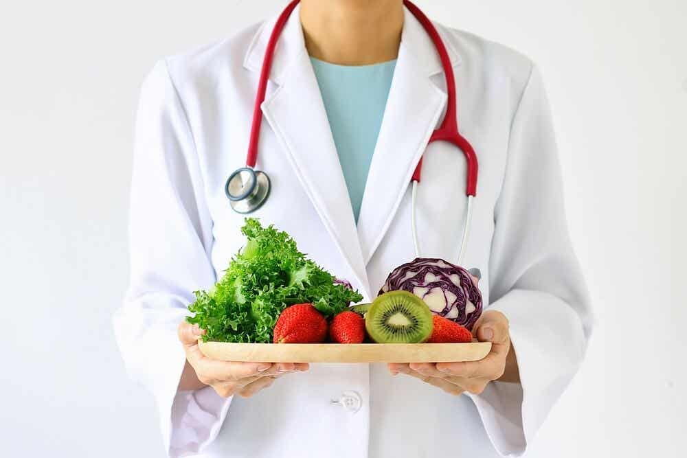 A doctor holding a cutting board full of fruits and vegetables.