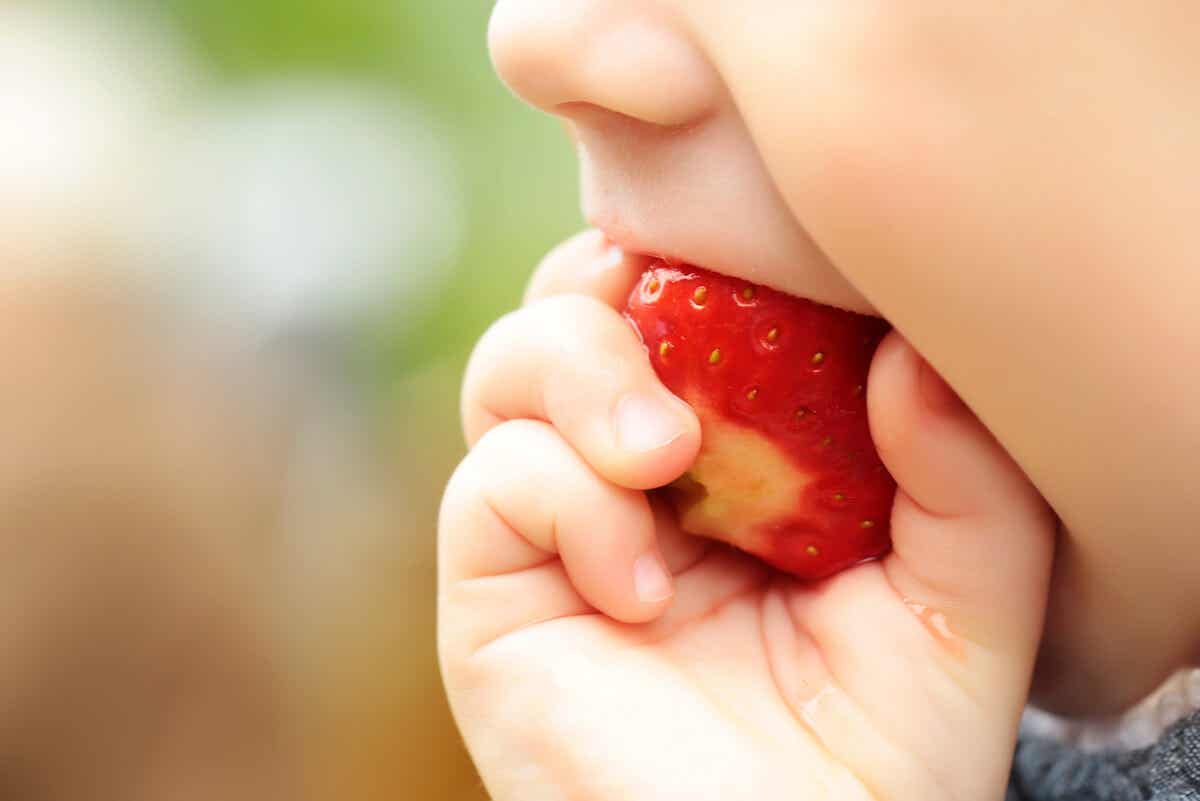 Ένα μωρό με σύνδρομο Sandifer τρώει μια φράουλα