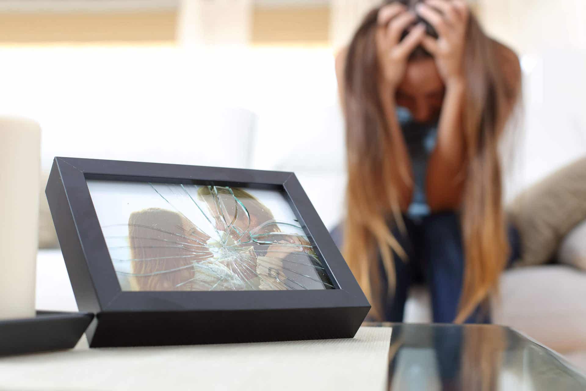A shattered picture of a happy couple in the foreground, with a distraught woman sitting on a couch in the background.