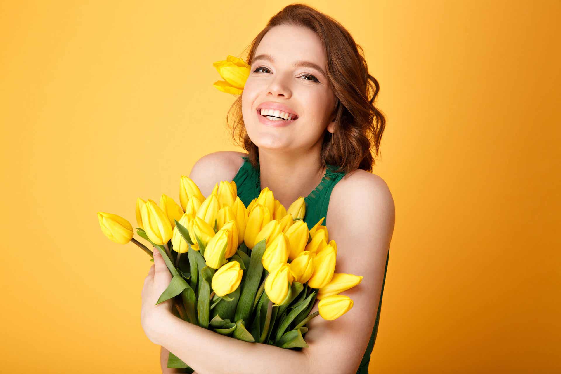 Smilende kvinde med tulipaner i favnen
