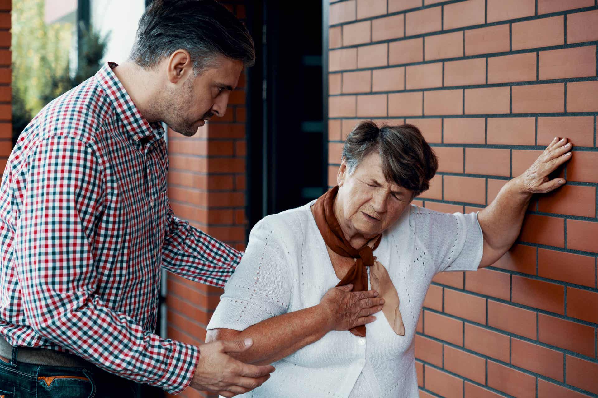 En mand, der hjælper en ældre kvinde, der ikke har det godt
