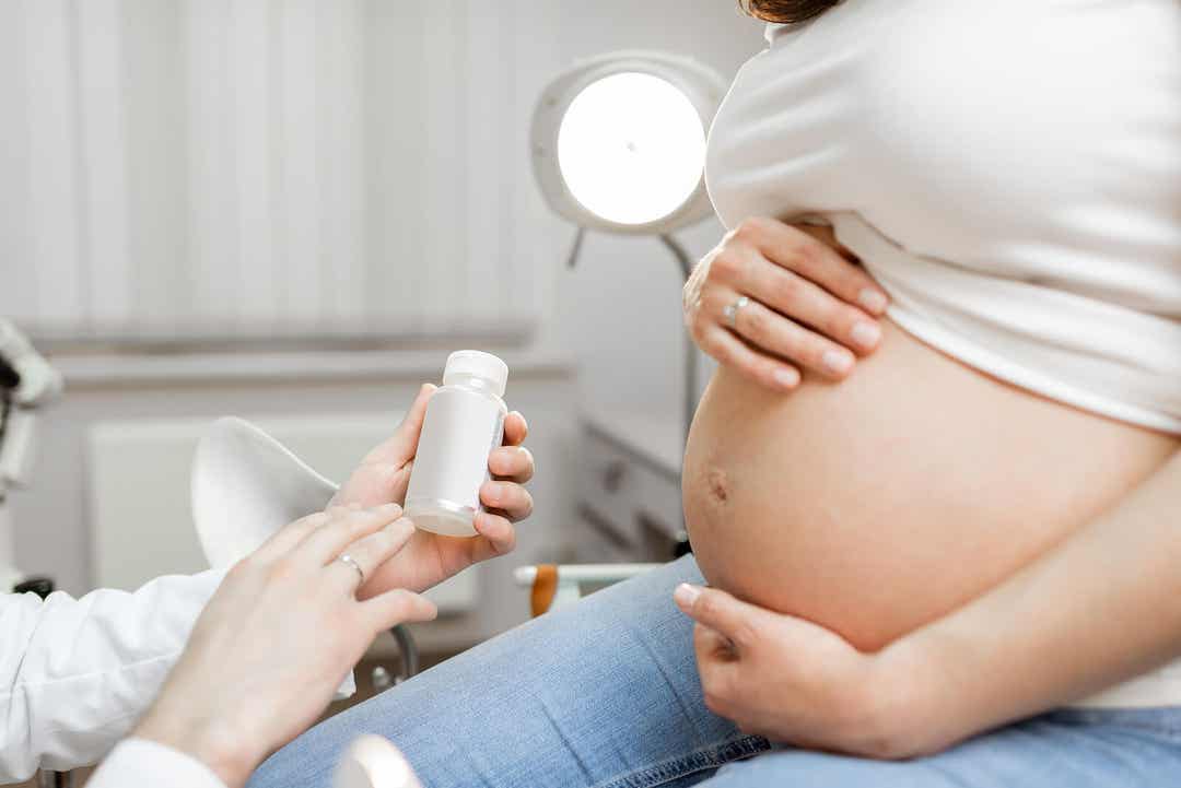 En læge, der forklarer noget om medicin til en gravid patient